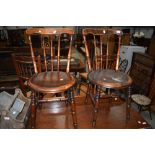 A pair of late Victorian dining chairs having patterned ply seats and turned frames, one seat