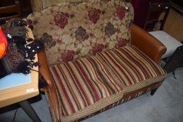 A modern part leather two seater settee, with brown leather arms and floral back in reds and browns,