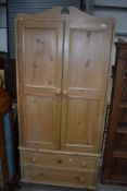 A natural pine wardrobe having two drawer base on bun feet, dimensions approx. H198 W88 D51cm