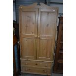 A natural pine wardrobe having two drawer base on bun feet, dimensions approx. H198 W88 D51cm