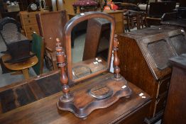 A Victorian mahogany toilet mirror having turned supports and shaped base with central circular