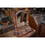 A Victorian mahogany toilet mirror having turned supports and shaped base with central circular