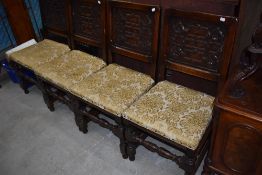 A set of four 19th Century oak dining chairs having carved panel backs and upholstered seats on