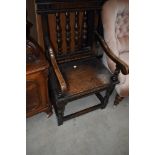 An unsual 19th Century oak and inlaid hall chair having turned spindle back and scroll arms