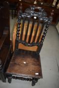 A 19th Century carved oak hall chair having solid seat, vine decoration to back rail, and part twist