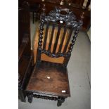 A 19th Century carved oak hall chair having solid seat, vine decoration to back rail, and part twist