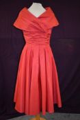 A 1950s bright pink taffeta dress having statement shawl collar, gathered waist and plated skirt