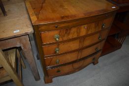 A reproduction walnut bow fronted chest of four long drawers, having brushing slide, labelled on