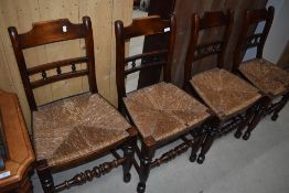 A set of four 19th Century spindle back kitchen chairs having rush seats, having rail and bobbin