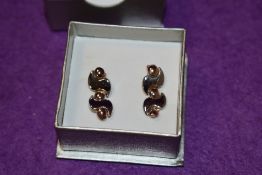 A pair of white and rose gold stud earrings having decorative articulated loops 1.8g