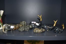 A selection of natural stone animals and a set of enamelled brass dolphins.