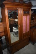 A Victorian mahogany mirror door wardrobe having glazed and curtained section and drawer base and