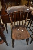 A traditional dark stained solid seat kitchen chair having spindle back