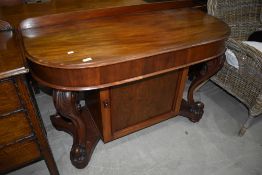 A Victorian mahogany console table having scroll legs, on castors, intergral cupboard, overall width