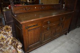 An early 20th Century oak ledge back sideboard in the Arts and Crafts style having ledge back,