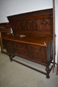 An early 20th Century oak sideboard having Gothic revival style panel back
