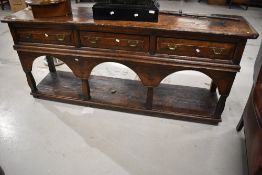 A period oak dresser base , possibly European having three frieze drawers and open shelf, with
