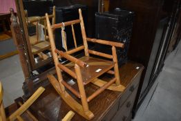 A vintage Victorian stained frame child's rocking chair having turned frame and ply seat