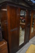 An early 20th Century mahogany triple wardrobe having mirror door, width approx. 158cm