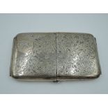 A large silver double opening cigarette case having scroll decoration with monogrammed cartouche and
