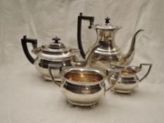 A four piece Edwardian silver tea set of plain oval form having gadrooned rims, hard wood and