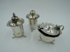 A silver three piece cruet set of cylindrical form having frilled rims, blue glass liner and trefoil