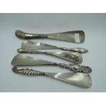 Five HM silver handled shoe horns of various forms including pistol style & shell