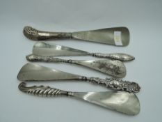 Five HM silver handled shoe horns of various forms including pistol style & shell