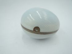 A white metal egg shaped trinket box having white enamelled guilloche decoration with gilt interior,