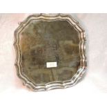 A silver salver having raised pie crust rim, hoof feet and presentation inscription to centre,