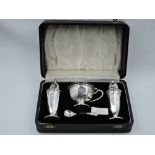 A cased silver three piece cruet set of facetted urn form, having blue glass liner, Sheffield 1949/