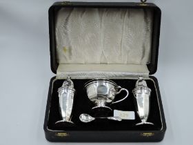 A cased silver three piece cruet set of facetted urn form, having blue glass liner, Sheffield 1949/