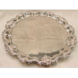 An Edwardian silver salver of circular form having raised pie crust rim with floral decoration,