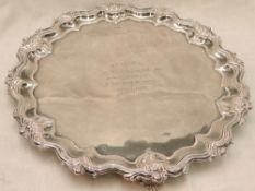 An Edwardian silver salver of circular form having raised pie crust rim with floral decoration,