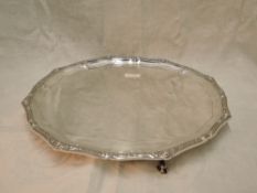 A silver salver of plain circular form having pie crust edge with Norse knot work border and hoof