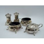 An Edwardian silver five piece cruet set of plain form having blue glass liners and paw feet,