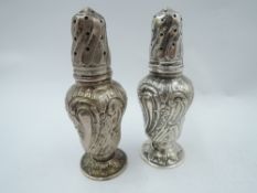A pair of Victorian/Edwardian silver pepperettes of baluster form having extensive floral and scroll