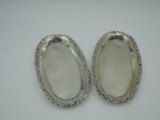 A pair of Edwardian silver trinket trays of oval form having moulded decoration to raised rim,