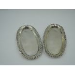 A pair of Edwardian silver trinket trays of oval form having moulded decoration to raised rim,