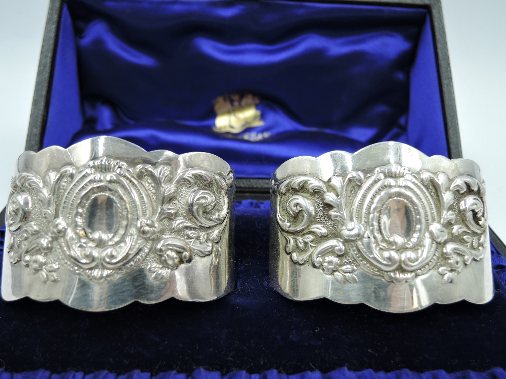 A cased pair of Victorian silver napkin rings of oval cuff form having repousse decoration to - Image 2 of 2