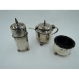 A silver three piece cruet set of plain cylindrical form on trefoil ball feet with blue glass