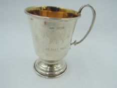 A small silver christening mug having gilt interior, monogram to side, loop handle and stepped