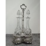 A Victorian silver plated three bottle gallery stand having bacchanalian moulded decoration to rims,