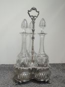 A Victorian silver plated three bottle gallery stand having bacchanalian moulded decoration to rims,