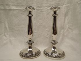 A pair of white metal candle sticks having moulded decoration to circular bases and baluster