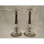 A pair of white metal candle sticks having moulded decoration to circular bases and baluster