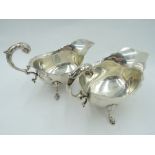 A pair of silver sauce boats having trefoil hoof feet, loop handles and shaped rims, Birmingham