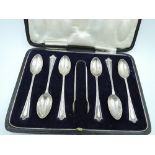 A cased set of six silver tea spoons with matching sugar nips having moulded decoration to