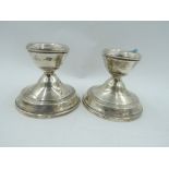 A pair of silver candle sticks of squat form with weighted bases, Birmingham 1968, W I Broadway