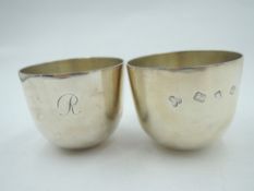 A pair of silver tumbler cups of plain form having curved weighted bases, initial J/R to side and